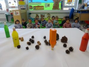 Los alumnos de Nursery 1 pintan con piñas y nueces para hacer un mural 