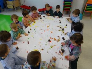 Los alumnos de Nursery 1 pintan con piñas y nueces para hacer un mural 