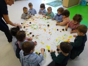 Los alumnos de Nursery 1 pintan con piñas y nueces para hacer un mural 