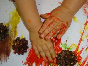 Los alumnos de Nursery 1 pintan con piñas y nueces para hacer un mural 