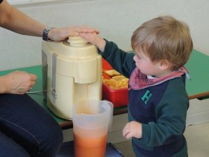 Conociendo los alimentos, los alumnos de Nursery 1 hacen zumo de frutas. 