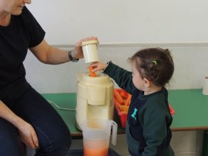 Conociendo los alimentos, los alumnos de Nursery 1 hacen zumo de frutas. 